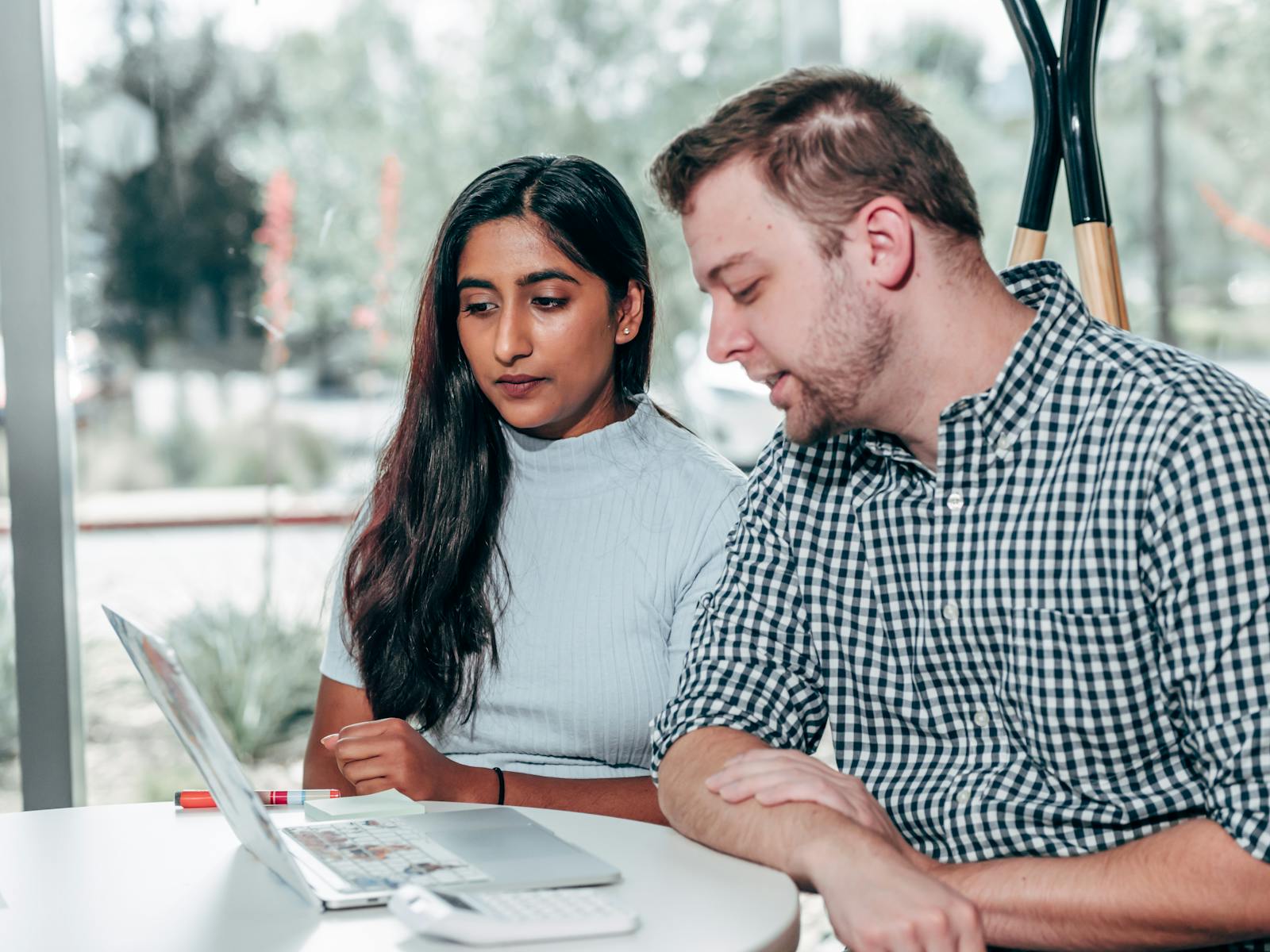 Two adults sitting at a table reviewing data on a laptop together